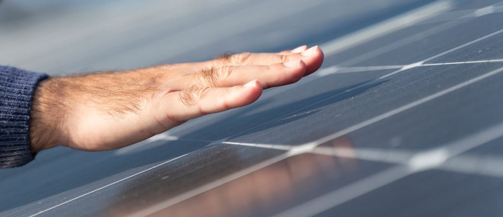Mann hält Hand über Solaranlage