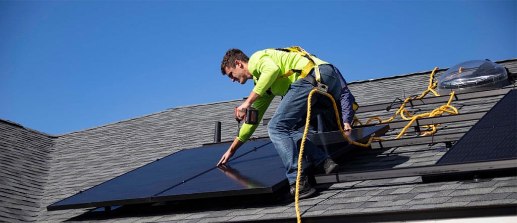 Mann bei der Montage einer Solaranlage auf dem Dach